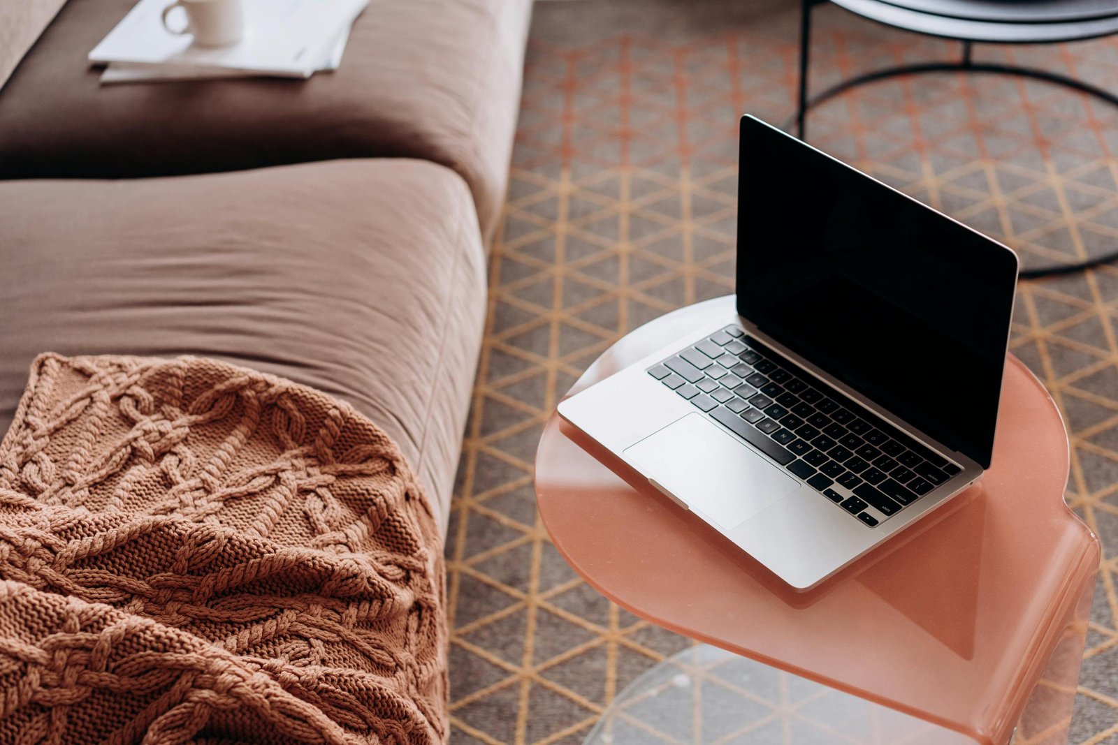 Laptop on a stylish side table in a cozy living room with soft furnishings.