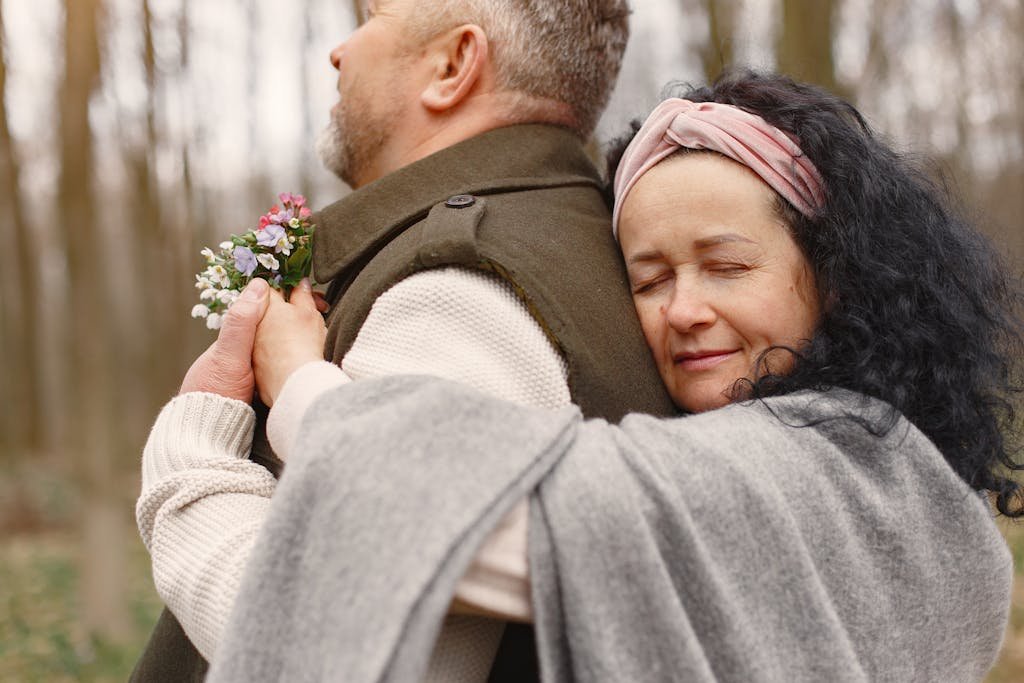 A couple sharing a tender moment with a back hug in an autumn forest.